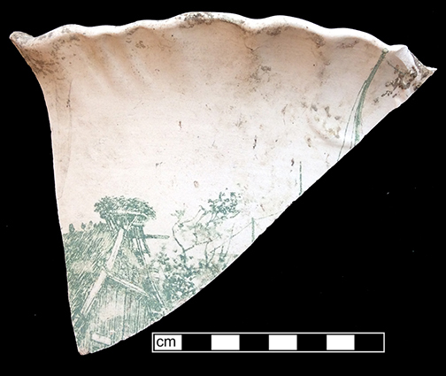 Unidentified hollow form, everted scalloped rim. Unglazed bisque waster. Transfer printed motif in dark green. Rim diameter: approx. 13.0”; 8.5 mm thickness.